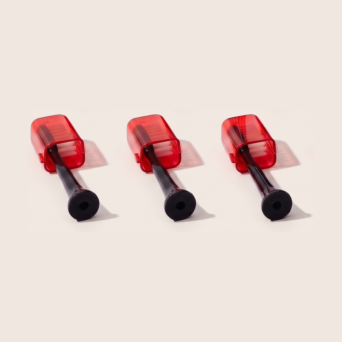 Close-up of three Solstra brush heads showing the translucent red cap and bristles