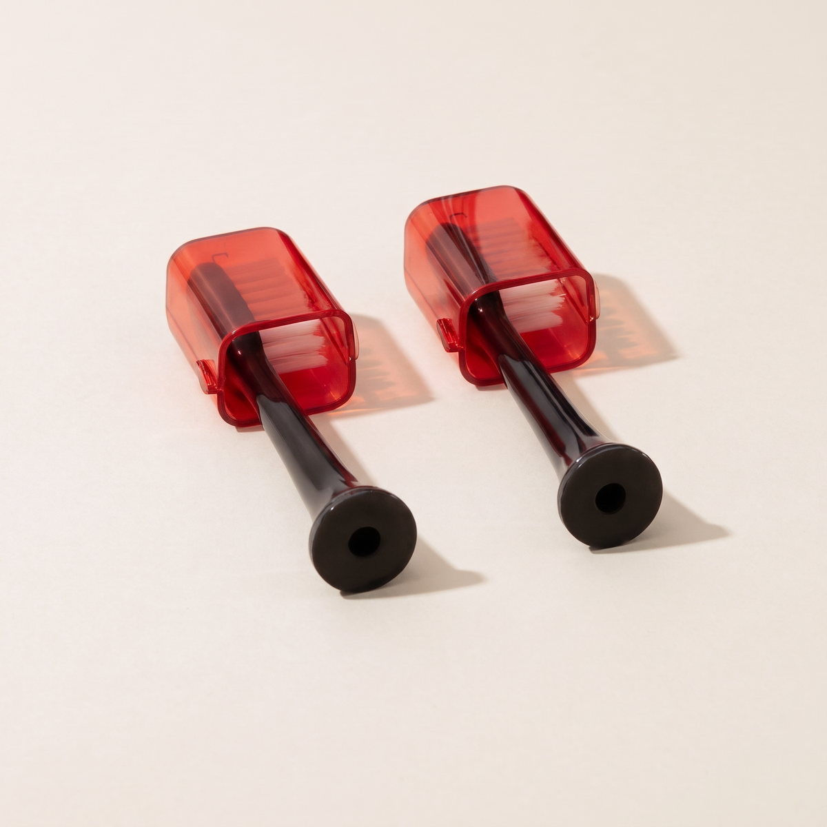 Two Solstra replacement brush heads with red caps, side by side on a cream background