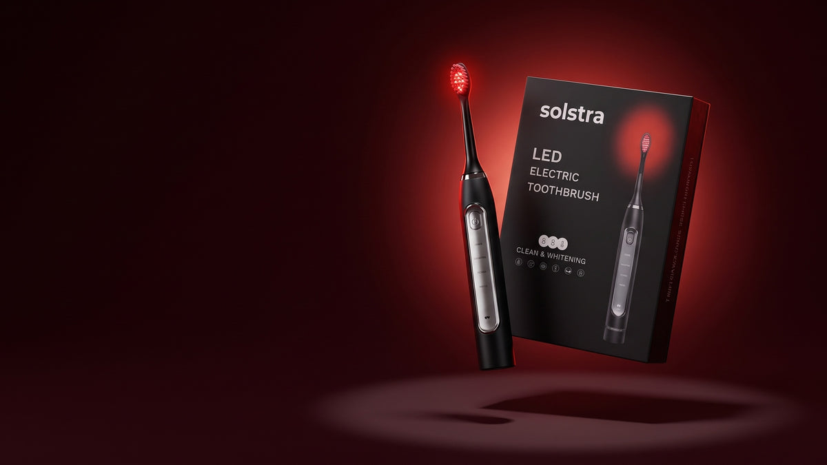The SOLSTRA Saliva-Boosting Toothbrush, its head glowing red, floating beside its box on a dark red background.