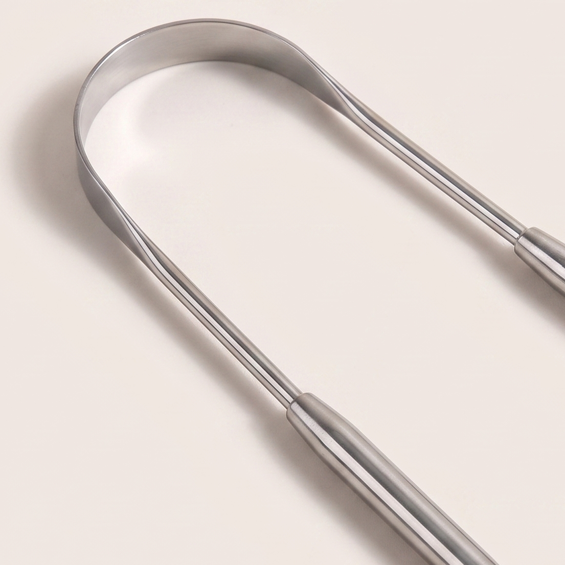 Close-up of the polished steel scraping edge of the tongue scraper